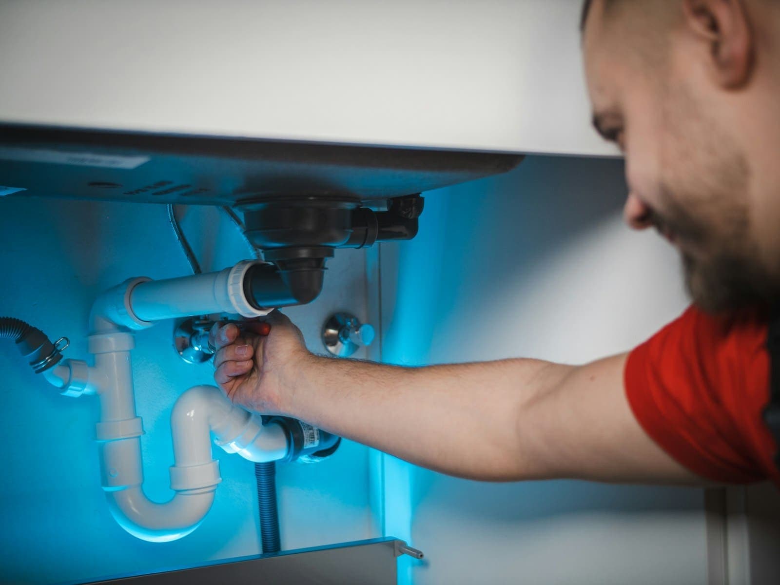 Licensed emergency plumber actively repairing a pipe at a DFW home